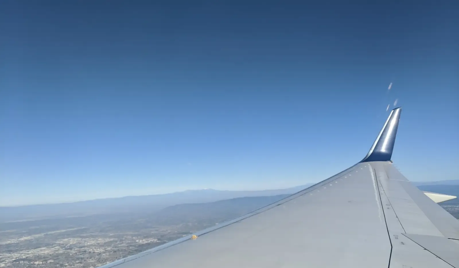 View from an airplane window over the wing and clouds.